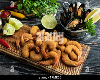 Les moules, crevettes pané frit servi avec de la chaux sur planche de bois, de délicieux, profonde rouge, la sauce blanche Banque D'Images