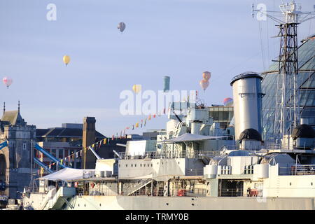 Le floatilla à partir de la Ricoh Lord-maire de Londres 2019 Régate Montgolfière passe au-dessus du Tower Bridge et HMS Belfast au petit matin. Banque D'Images