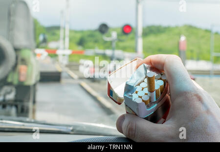 Vue de la part du pilote avec un paquet de cigarettes sur le volant de la voiture, qui s'est arrêté devant un passage à niveau fermé à un feu rouge Banque D'Images