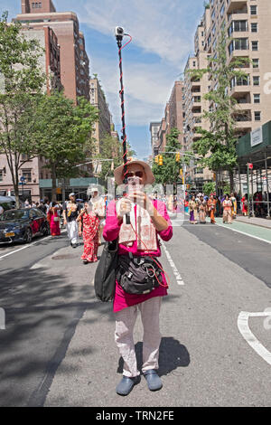 Un homme à l'avant du défilé de Hare Krishna Ratha Yatra à New York à la fois prend une photos & selfies le défilé avec une caméra go pro a fait l'arrière. Banque D'Images