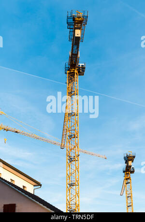 Tall yellow plusieurs grues de construction industrielle au milieu d'un quartier résidentiel Banque D'Images