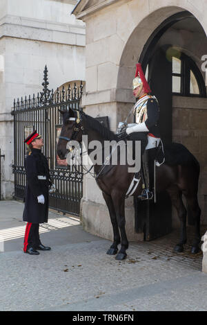 Dans la région de Whitehall, un cavalier monté de la Household Cavalry parle avec un agent. Banque D'Images