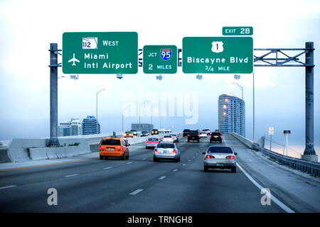 Miami, FL, USA - 12 mai 2013 : Soirée le trafic sur l'autoroute, Miami, USA. Les wagons sur une route avec des panneaux à l'aéroport international de Miami, Banque D'Images