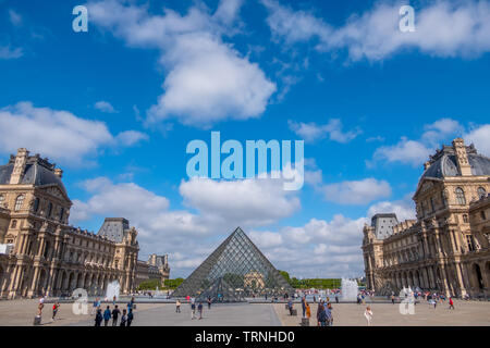 La France. L'été ensoleillé à Paris. La célèbre cour du Louvre Museum et la pyramides de verre. De nombreux touristes. Nuages Banque D'Images