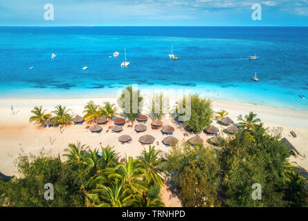 Vue aérienne de parasols, palmiers sur la plage de sable de l'Océan Indien à la journée ensoleillée. Vacances d'été à Zanzibar, Afrique. Paysage tropical avec palmier Banque D'Images
