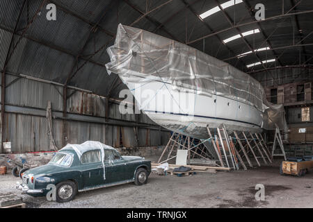 Crosshaven, Cork, Irlande. 10 Juin, 2019. Un vieux classique Rover 110 voiture et un yacht de course de l'océan, dans l'entreposage à Crosshaven, co Cork, Irlande. Banque D'Images