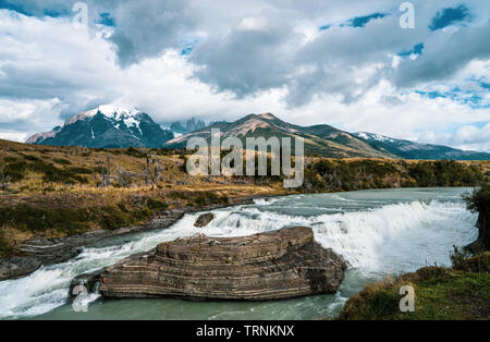 Les trois tours de montagnes et du Parc National Torres del Paine ajouter un cadre dramatique à la paine jaillissante cascade dans l'avant-plan. Banque D'Images