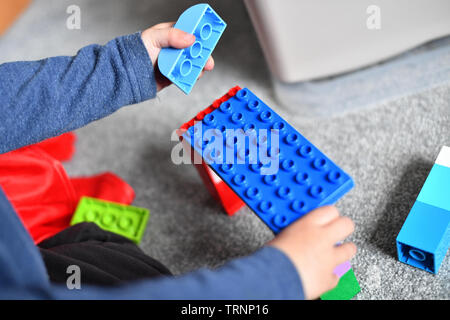 Un garçon en robe d'un capuchon et le masque joue avec des blocs Lego Duplo Banque D'Images