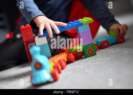 Un garçon en robe d'un capuchon et le masque joue avec des blocs Lego Duplo Banque D'Images