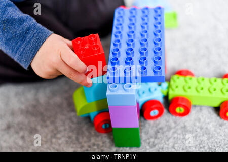 Un garçon en robe d'un capuchon et le masque joue avec des blocs Lego Duplo Banque D'Images