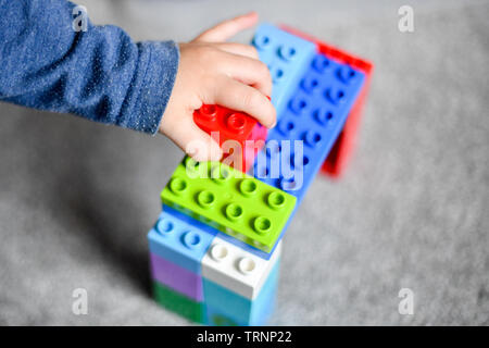 Un garçon en robe d'un capuchon et le masque joue avec des blocs Lego Duplo Banque D'Images