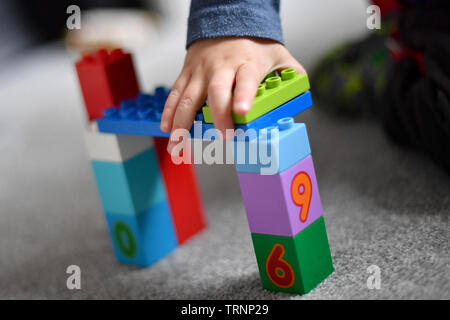 Un garçon en robe d'un capuchon et le masque joue avec des blocs Lego Duplo Banque D'Images