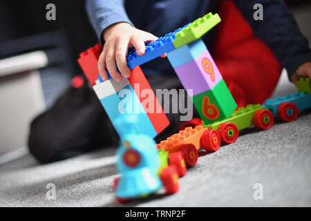 Un garçon en robe d'un capuchon et le masque joue avec des blocs Lego Duplo Banque D'Images