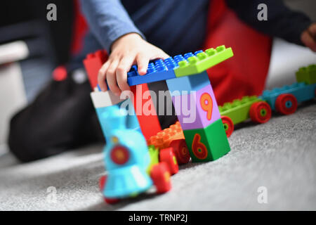 Un garçon en robe d'un capuchon et le masque joue avec des blocs Lego Duplo Banque D'Images