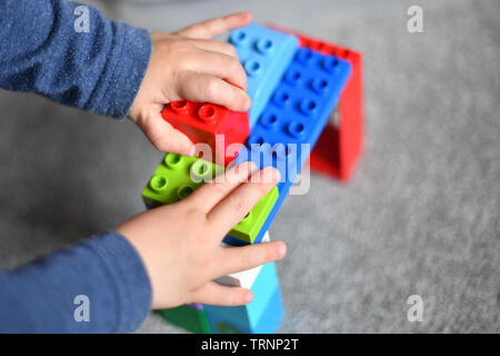 Un garçon en robe d'un capuchon et le masque joue avec des blocs Lego Duplo Banque D'Images