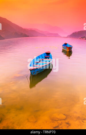 Deux bateaux en stationnement Lac Phewa,et de Soleil colorés sur fond.Pokhara Népal Banque D'Images