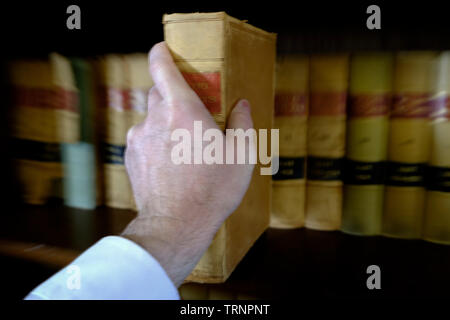 Hand Reaching for book arrachant shelf in library Banque D'Images