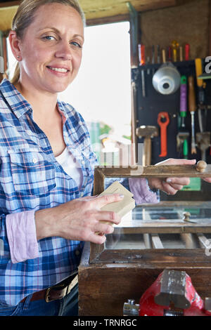 Portrait de femme mature à l'atelier de meubles Upcycling Accueil Ponçage avec du papier de verre du Cabinet Banque D'Images