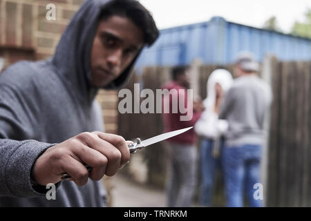 Teenage Boy in Gang urbain pointant vers la caméra du couteau Banque D'Images