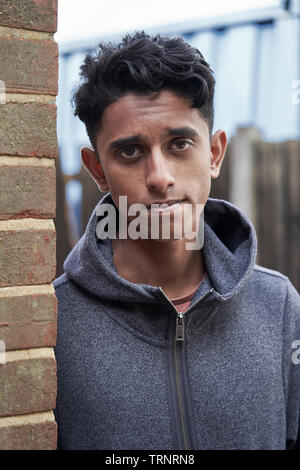 Portrait of Teenage Boy Leaning Against Wall In Urban Setting Banque D'Images