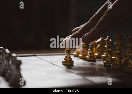 L'homme jouant aux échecs jeu stratégie sur l'échiquier,meubles concept fort avec un arrière-plan sombre. Banque D'Images