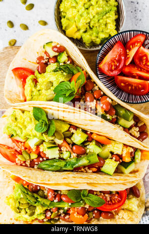 Vegan tortillas avec le quinoa, les asperges, les haricots, les légumes et le guacamole. Banque D'Images