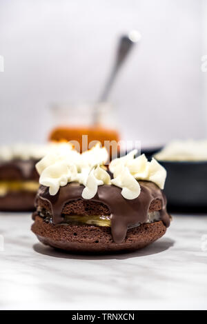 Le style viennois Sachertorte (gâteau) Donut avec confiture d'abricot et d'Amandes au centre, recouvert de chocolat fondu, décoré avec de la crème fouettée Banque D'Images