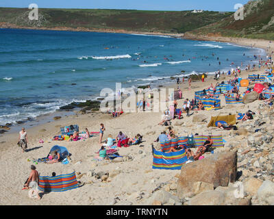 Les gens qui profitent d'une journée d'été ensoleillée sur la plage de Sennen Cove, Cornwall, Angleterre, Royaume-Uni montrant la plage de sable et la mer bleue sous un ciel bleu. Banque D'Images