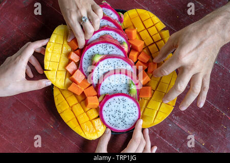 Assortiment de fruits tropicaux et les gens les mains, Close up. Délicieux dessert. Groupe d'amis heureux d'avoir la bonne cuisine, profiter de la partie et la communication. M Banque D'Images