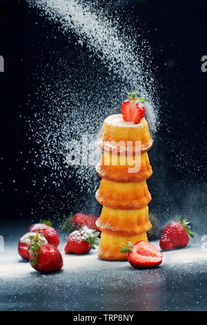 Un plat de muffins aux fraises crème au beurre et saupoudrer de sucre en poudre de remplissage Banque D'Images
