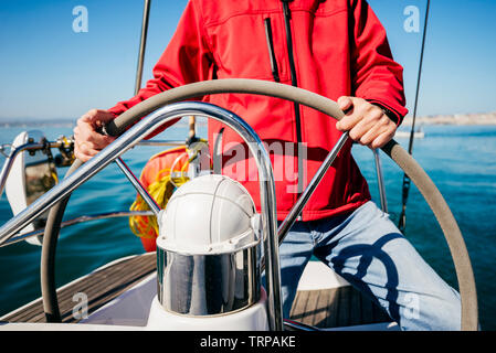 Homme méconnaissable avec red jacket conduisant le voilier volant dans la mer Banque D'Images