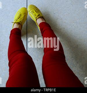 La section basse partie du corps de la femme en pantalon rouge et vert chaussures Banque D'Images