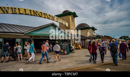 Les touristes et vacanciers de marcher le long de la mer au-delà de la jetée de Wellington sur le Golden Mile de la ville côtière de Great Yarmouth, Norfolk Banque D'Images