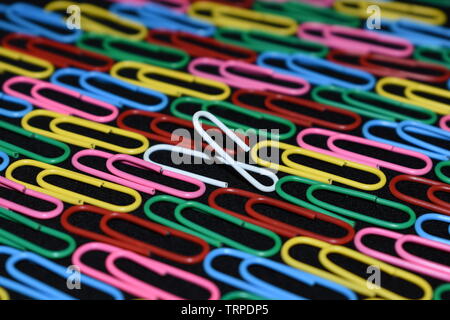 Trombones multicolores avec un trombone blanc entre eux. Banque D'Images