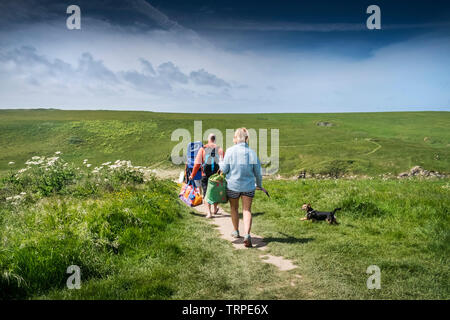 Une famille de vacanciers et leur chien en vacances sur une promenade le long d'un sentier menant à Polly Porth Joke à Newquay, en Cornouailles. Banque D'Images