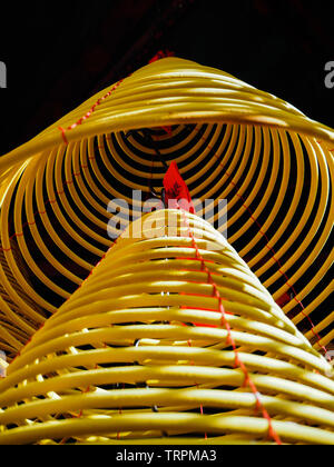 Plusieurs grandes bobines encens jaune accroché en piles à partir du plafond dans un temple chinois Banque D'Images