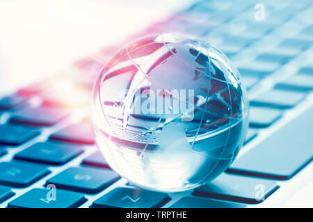 Concept commercial informatique mondial avec petit globe on laptop keyboard Banque D'Images