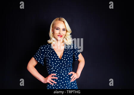 Portrait de studio de belle blonde femme dans une robe bleu foncé noir contre fond uni Banque D'Images
