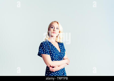 Portrait de studio de belle blonde femme dans une robe bleu foncé blanc contre fond uni Banque D'Images