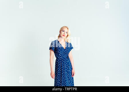 Portrait de studio de belle blonde femme dans une robe bleu foncé blanc contre fond uni Banque D'Images