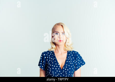 Portrait de studio de belle blonde femme dans une robe bleu foncé blanc contre fond uni Banque D'Images