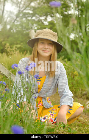 Teenage girl portrait portant un chapeau et assis près de baccalauréat en fleurs bouton sur une ferme Banque D'Images