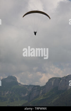 Un homme navigue à travers les nuages, au-dessus de la Suisse Edelweiss en parapente. Banque D'Images