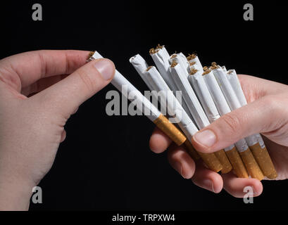 La main est de donner des paquet de cigarettes sur fond noir Banque D'Images