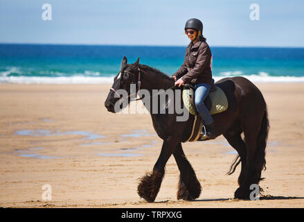 Une femme montant un cheval sur une plage à Cornwall Banque D'Images