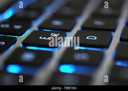 Clavier d'ordinateur portable avec rétroéclairage bleu. Gros plan montrant les détails des boutons noir, lettres blanches et corps argent. Banque D'Images