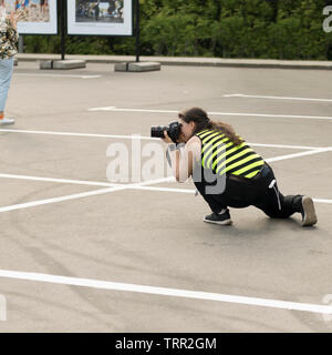 Une femme photographe avec appareil photo reflex numérique est secrètement prendre des photos de quelqu'un en exposition à l'extérieur. Moscou - 1er juin 2019. Photographiant cachés, pap Banque D'Images