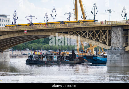 Grue et d'exploitation des bateaux de travail sur le site d'un accident où deux bateaux se sont abordés dans le cadre du pont sur le Danube, avec un tramway passant. Banque D'Images