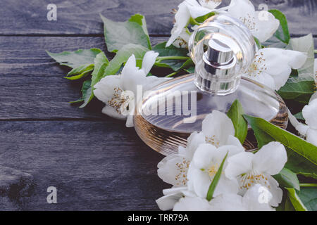 Flacon de parfum avec fleurs de jasmin sur fond de bois. Parfum de femmes avec l'odeur de jasmin. Banque D'Images