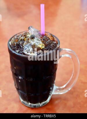 L'heure du café, un verre de café glacé sucré et noir sur la table. Banque D'Images